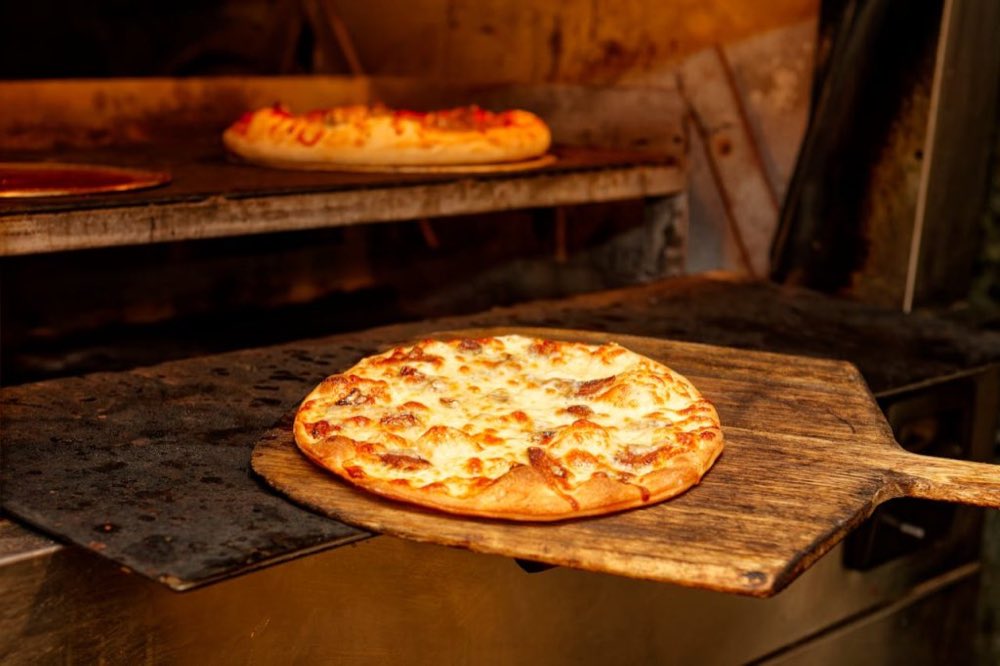 Pizza appena sfornata sulla pala di legno